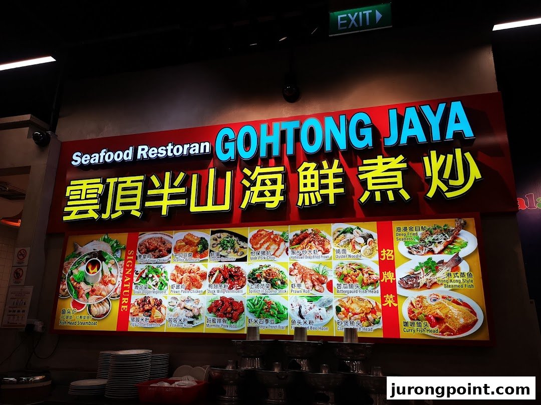 A large illuminated sign for Seafood Restoran GOHTONG JAYA, displaying various seafood and local dishes with photos.