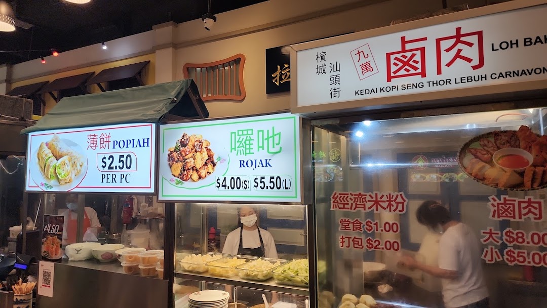 A vibrant food stall display showcasing various Malaysian hawker dishes with prices and descriptions.