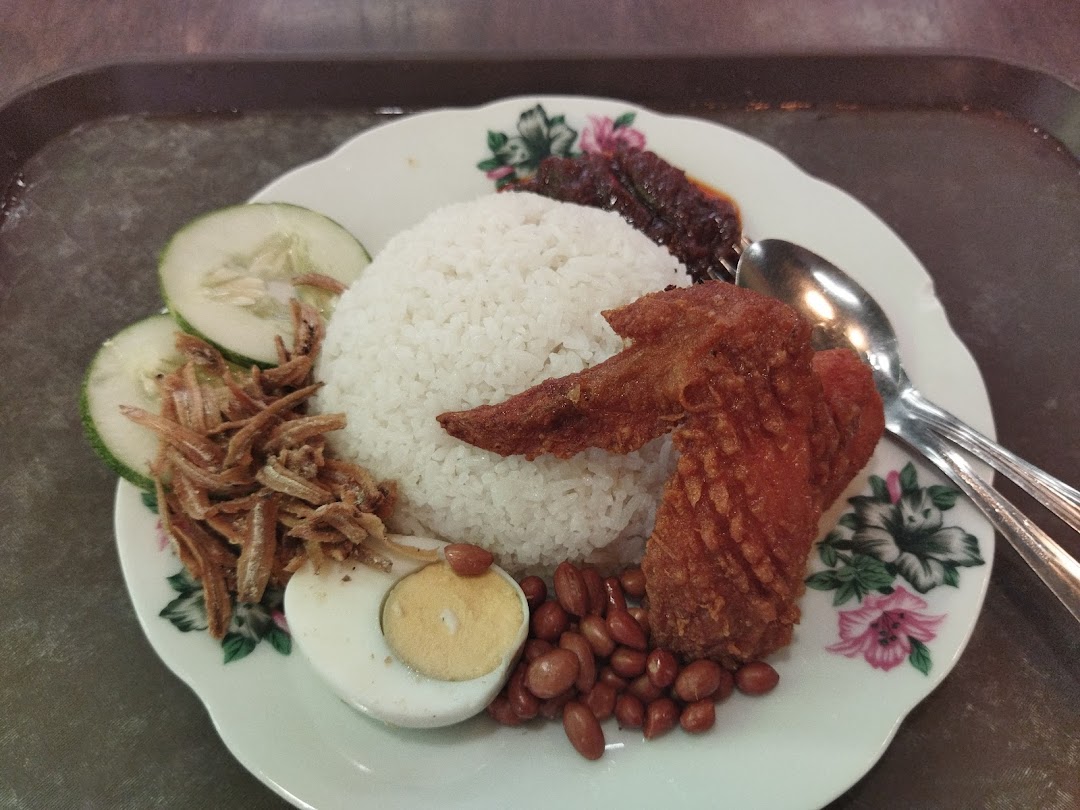 A delicious plate of Nasi Lemak with fried chicken, anchovies, peanuts, egg, and cucumber.