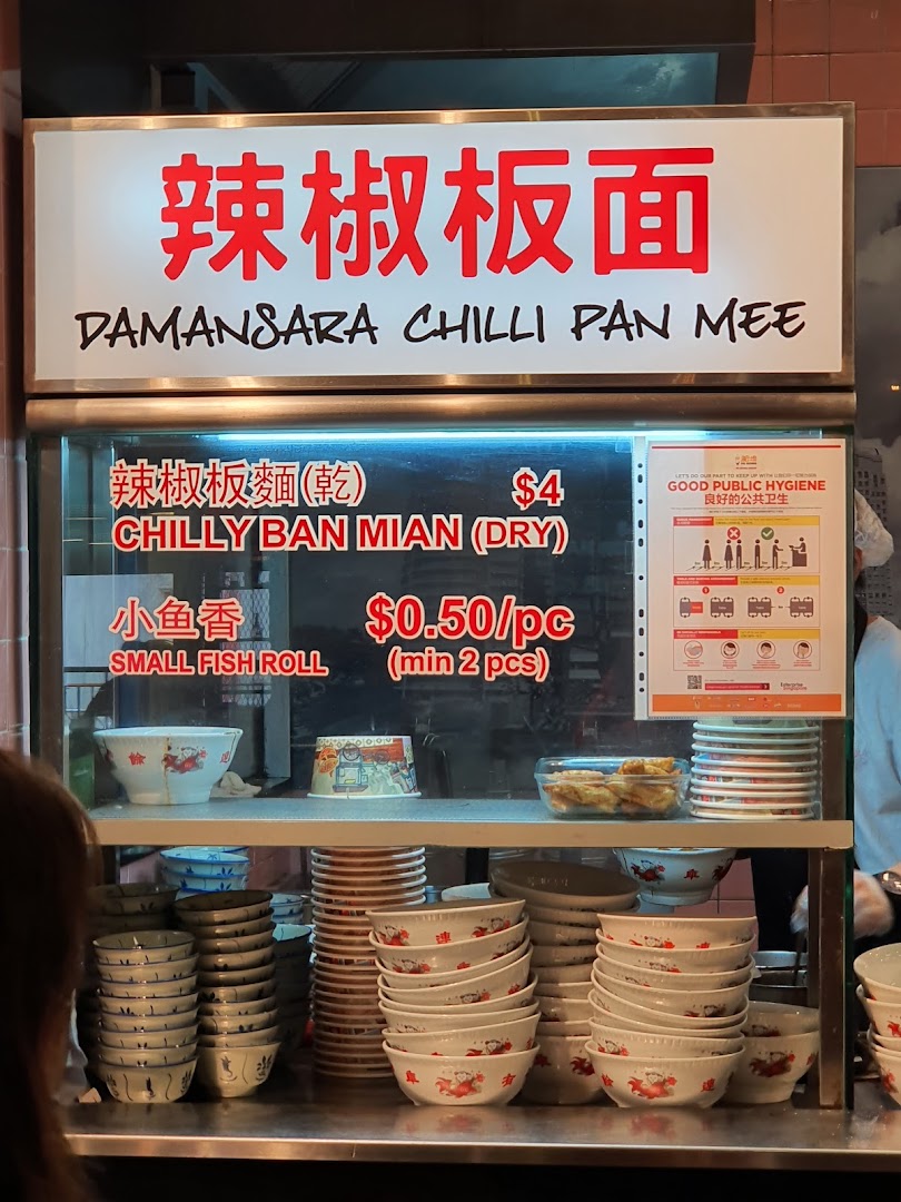 A food stall counter displaying its menu for Damansara Chilli Pan Mee and Small Fish Rolls.