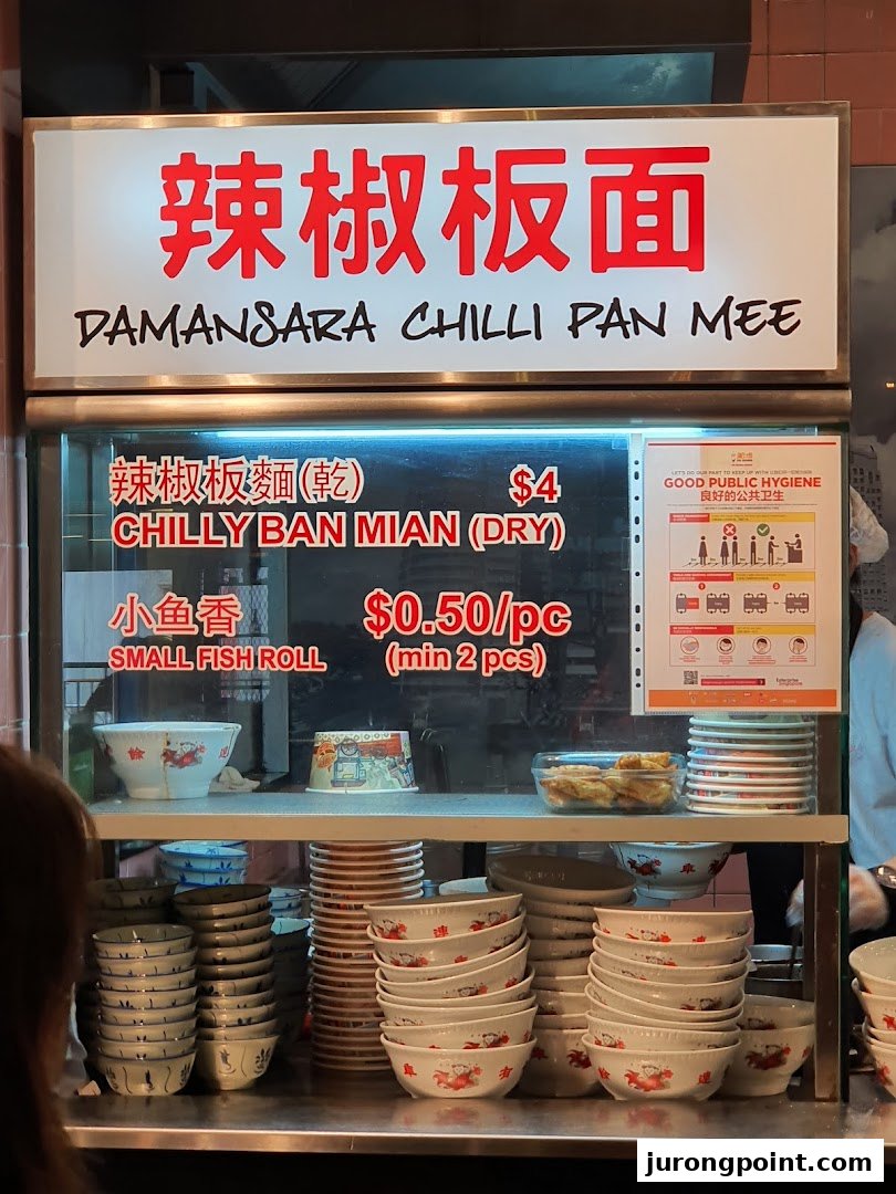 A food stall counter displaying its menu for Damansara Chilli Pan Mee and Small Fish Rolls.