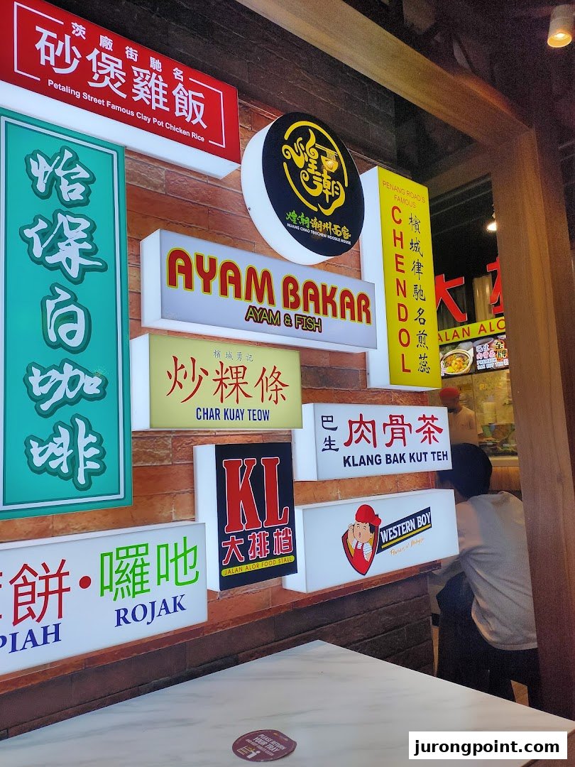 A vibrant wall display showcasing various Malaysian food options like Clay Pot Chicken Rice, Ayam Bakar, and Rojak.