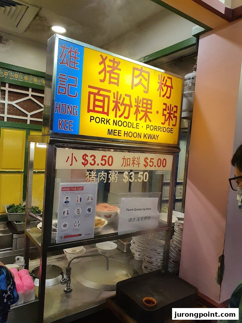 A food stall's menu board displaying traditional noodle and porridge dishes with prices.