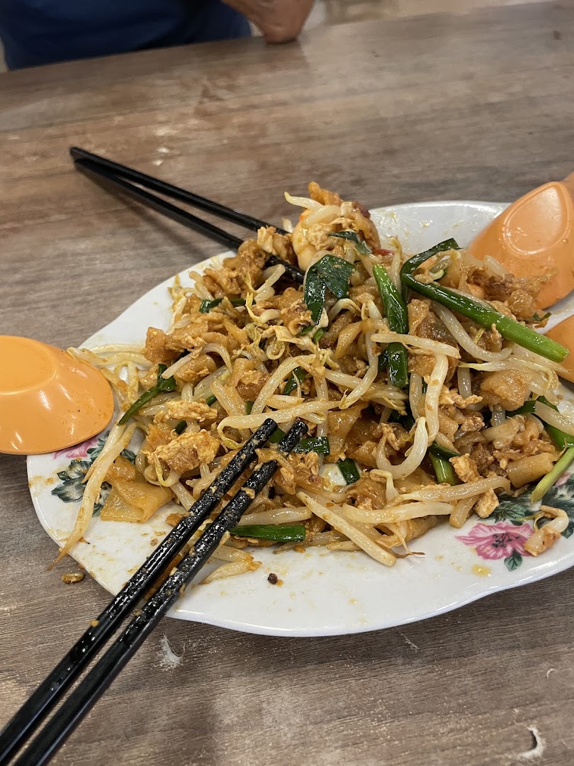 A close-up of a delicious plate of stir-fried noodles with bean sprouts and eggs, served with chopsticks.