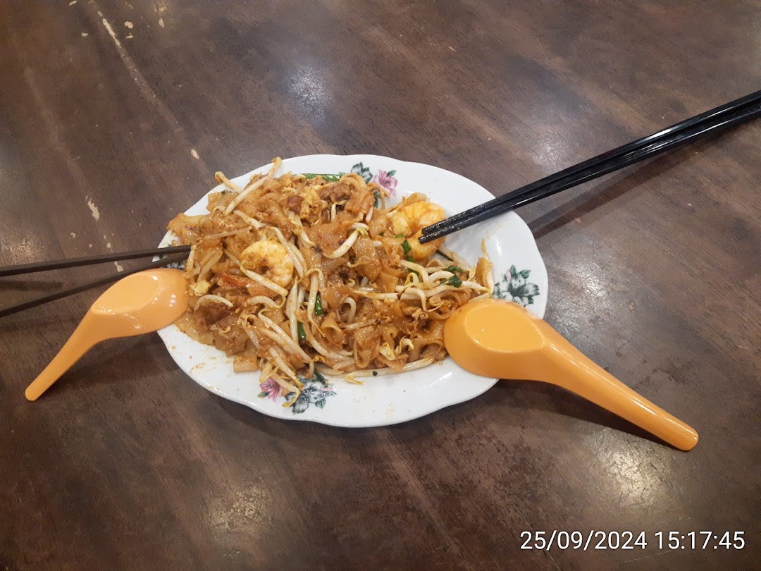 A delicious plate of Char Kway Teow with prawns and bean sprouts on a wooden table.