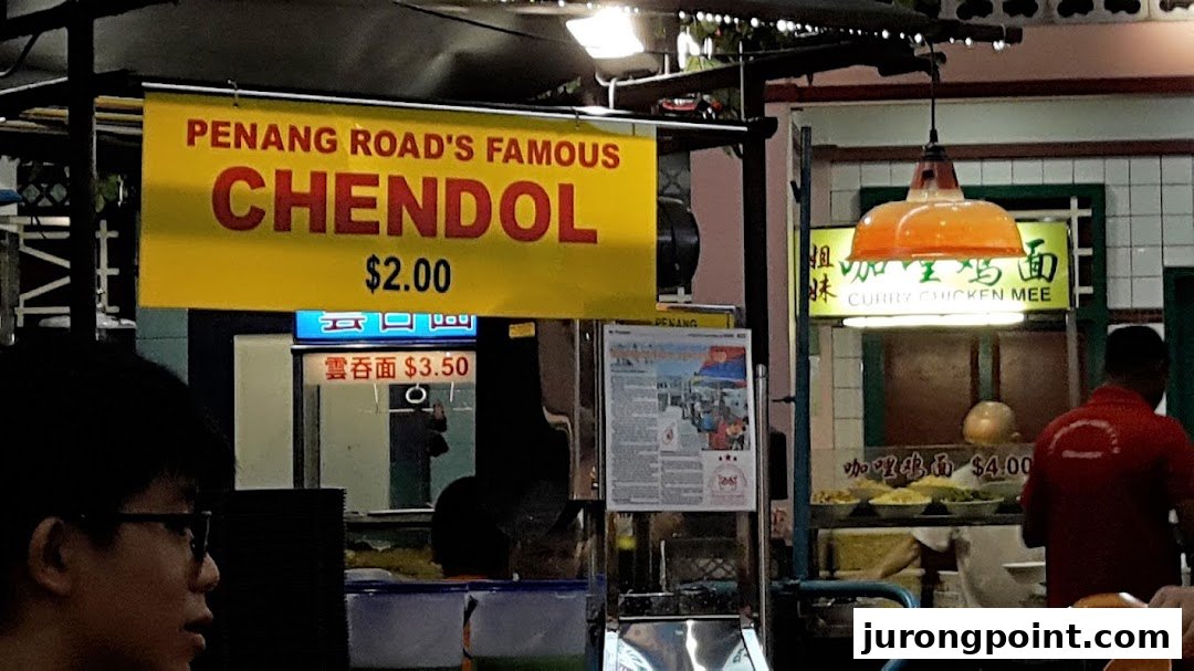 A vibrant food stall showcasing popular Malaysian dishes like Chendol, Wonton Mee, and Curry Chicken Mee with prices.