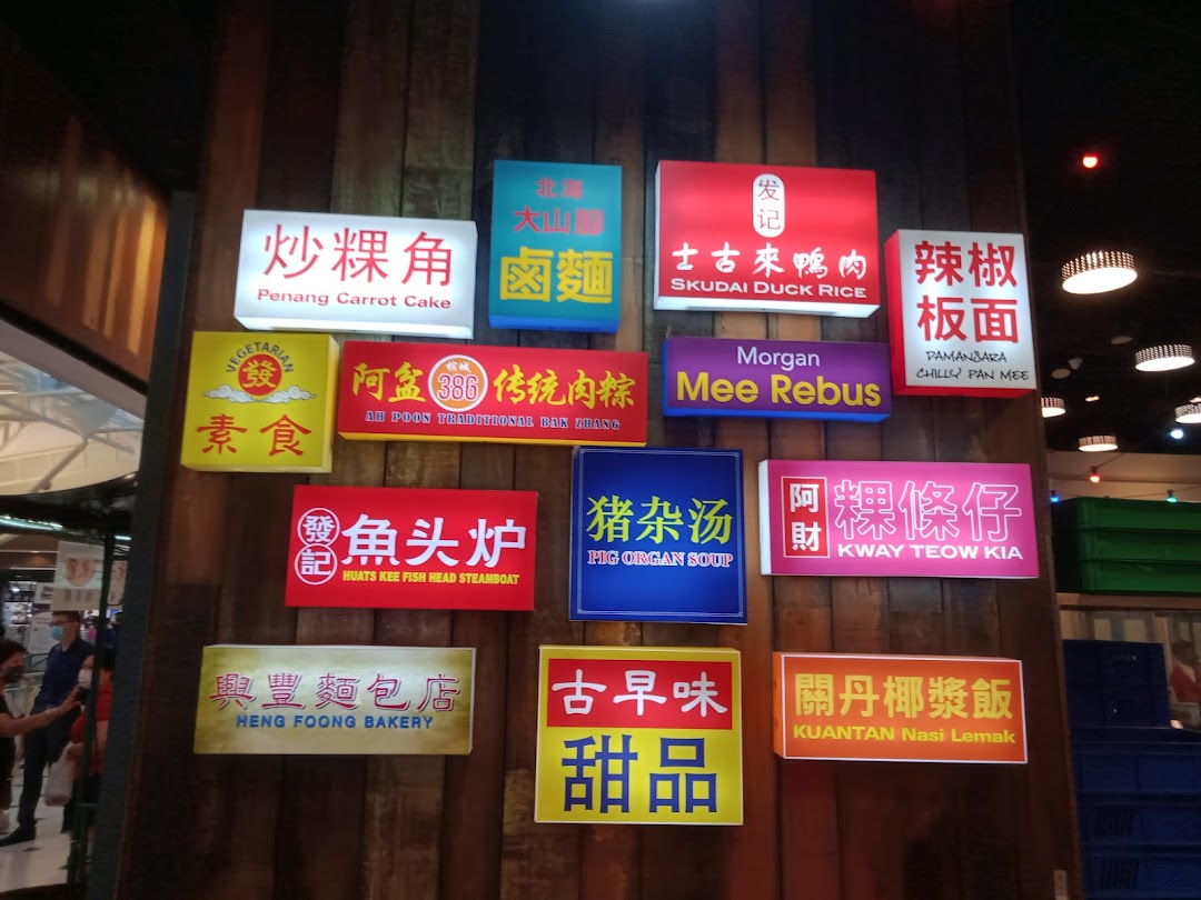 Illuminated signs on a wooden wall showcasing a variety of Malaysian food stalls and dishes.