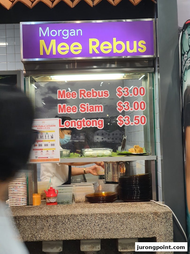 A food stall displaying its menu for Mee Rebus, Mee Siam, and Longtong with prices.