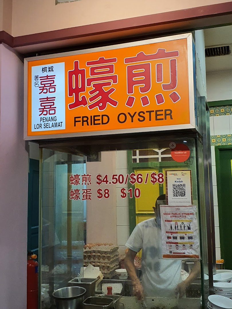 A food stall sign for 'Fried Oyster' with prices and a chef preparing dishes.