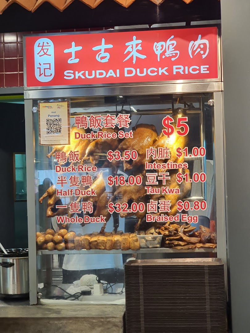 A food stall display featuring roasted ducks and a menu with prices for duck rice and side dishes.
