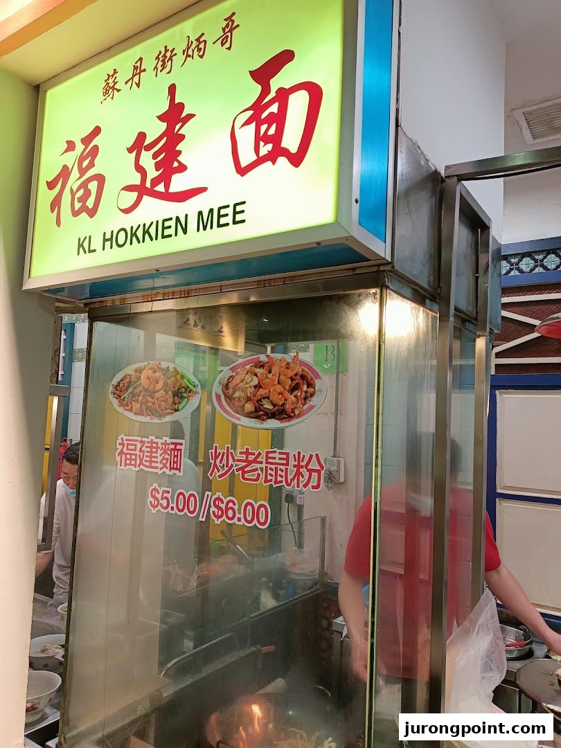 A food stall sign for KL Hokkien Mee, displaying dishes and prices.