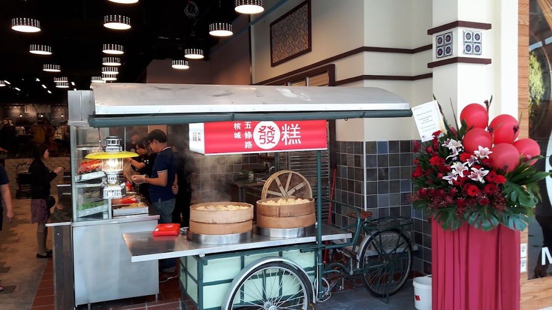 A bustling food stall with steaming dim sum baskets and customers, featuring a traditional bicycle cart and floral decor.