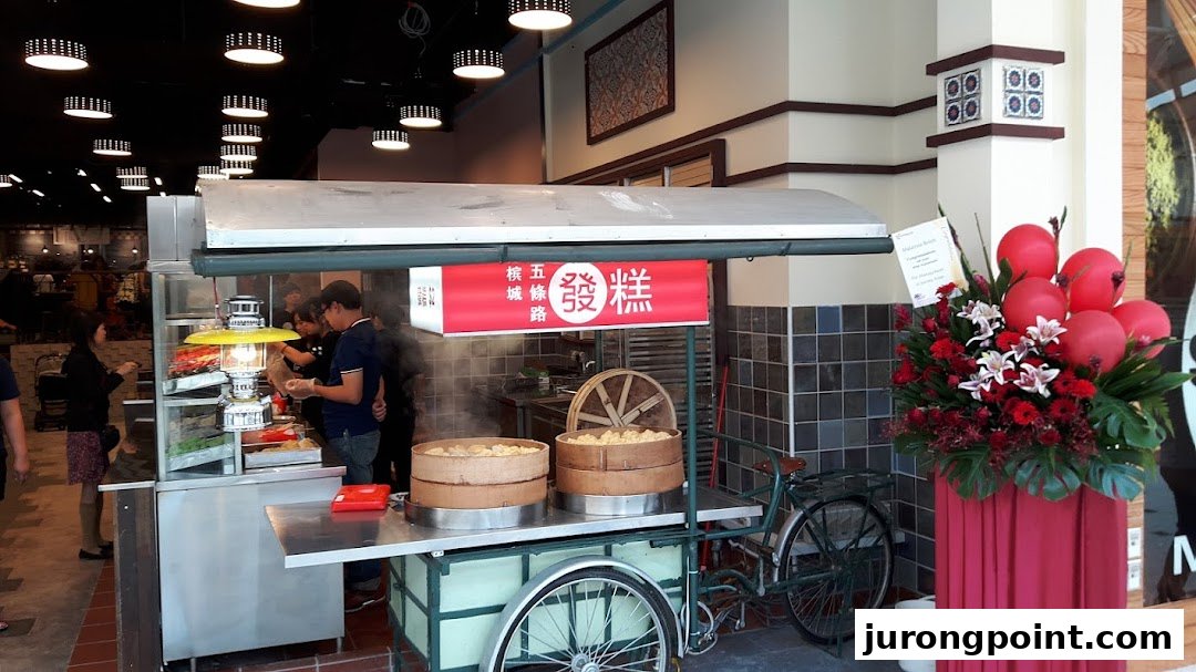A bustling food stall with steaming dim sum baskets and customers, featuring a traditional bicycle cart and floral decor.