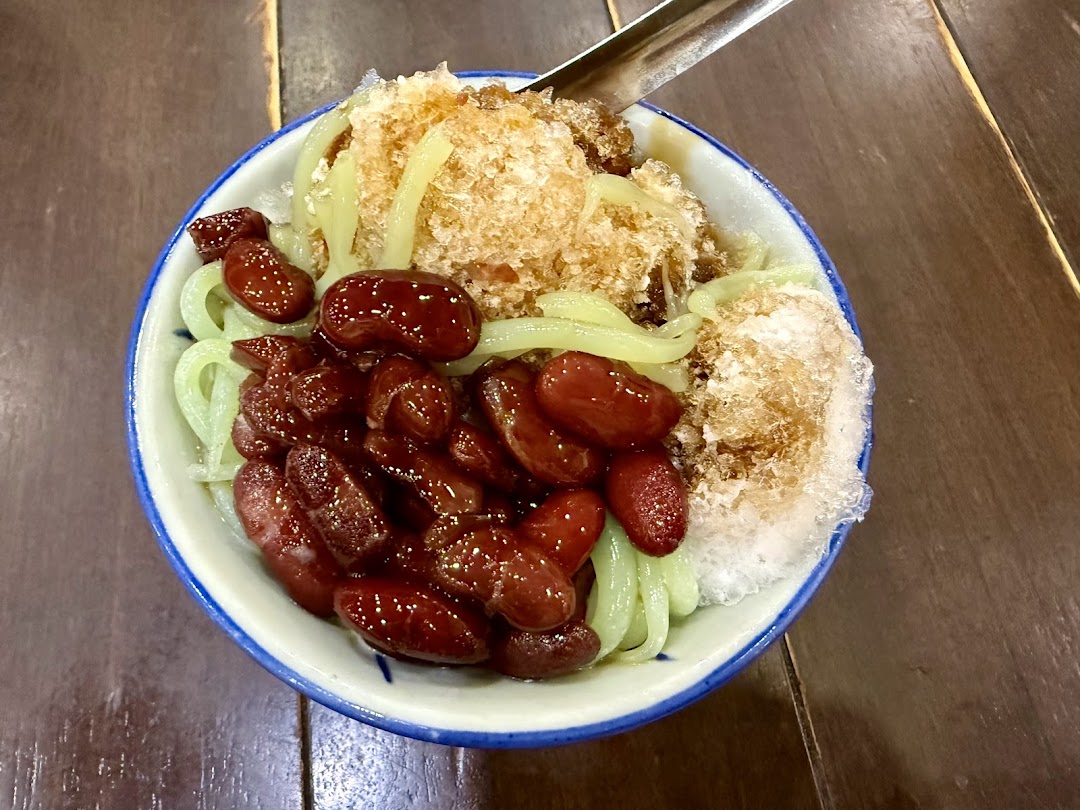 A vibrant bowl of traditional Malaysian dessert with red beans, green cendol, and shaved ice.