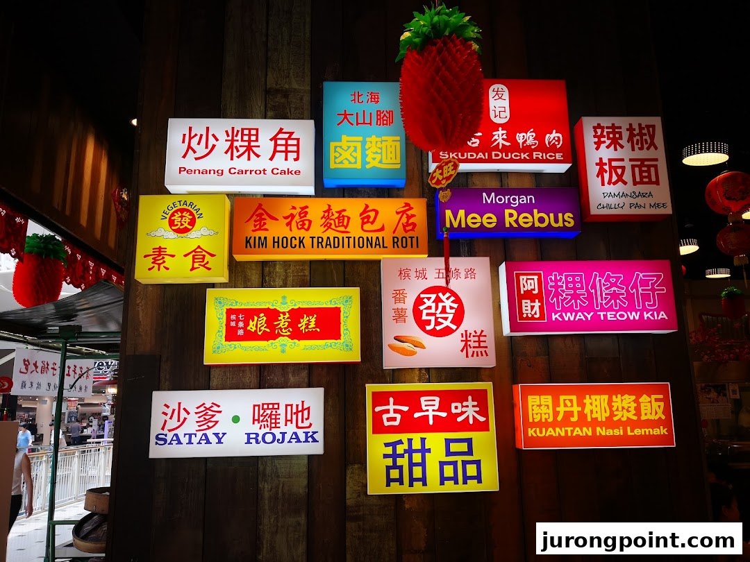 Illuminated signs showcasing various Malaysian hawker dishes on a rustic wooden wall.