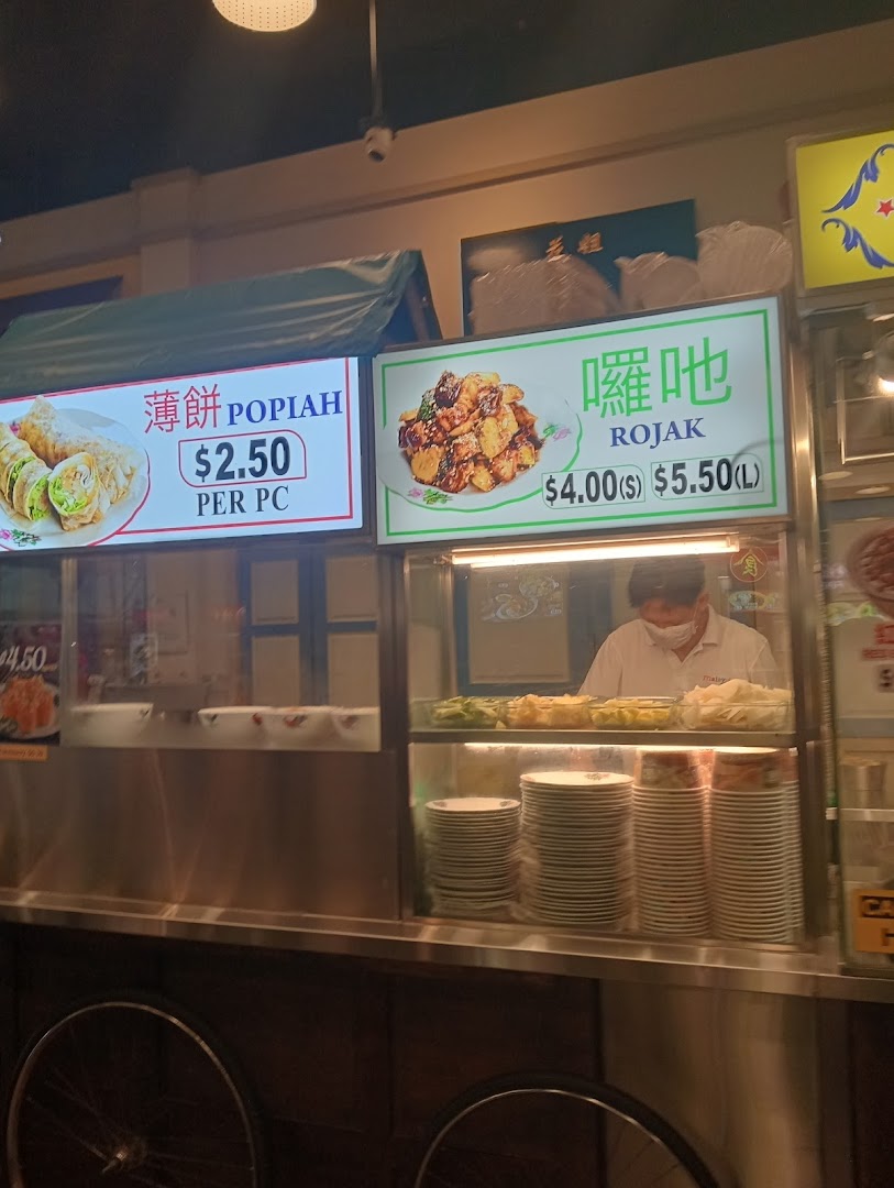 A food stall counter at Malaysia Boleh! displaying menu items like Popiah and Rojak with prices.