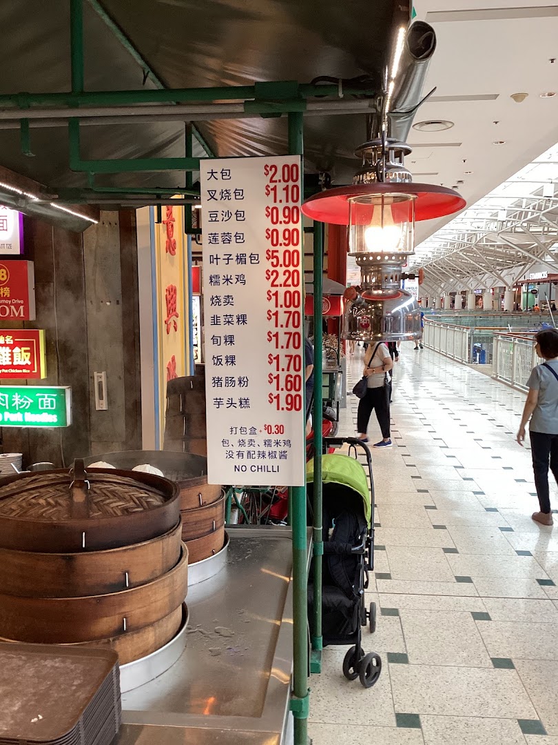 A food stall displaying a menu board with prices for various steamed buns, dim sum, and traditional snacks.