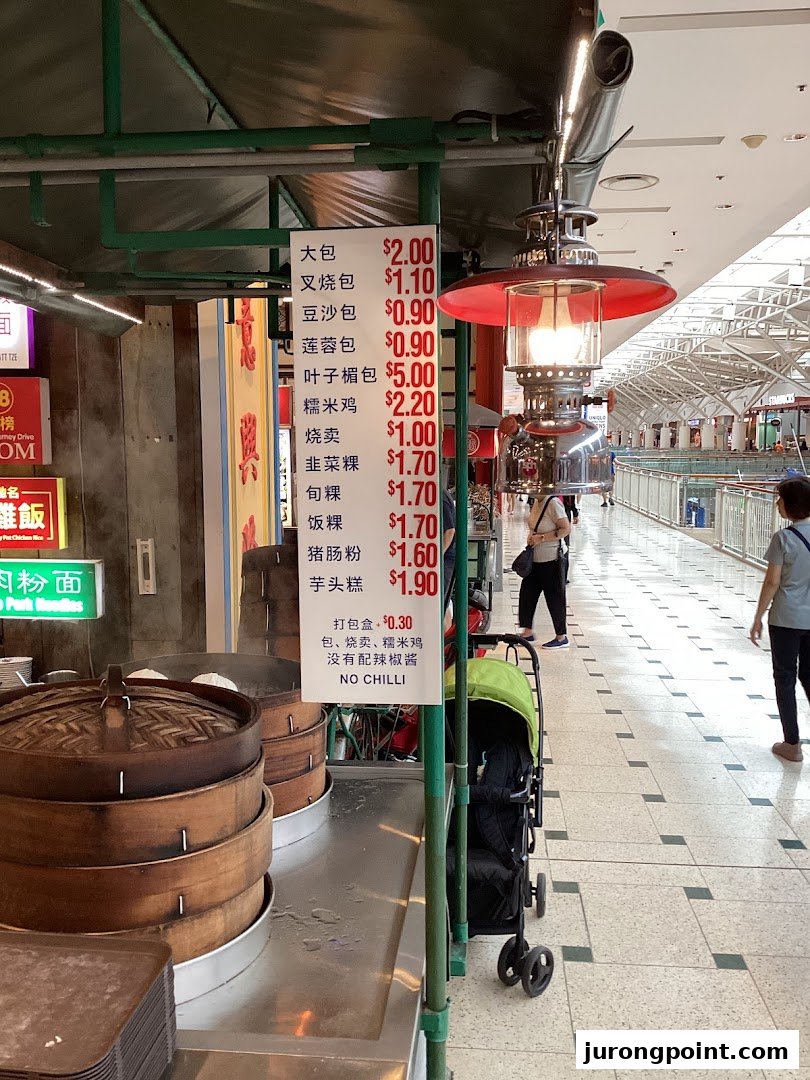 A food stall displaying a menu board with prices for various steamed buns, dim sum, and traditional snacks.