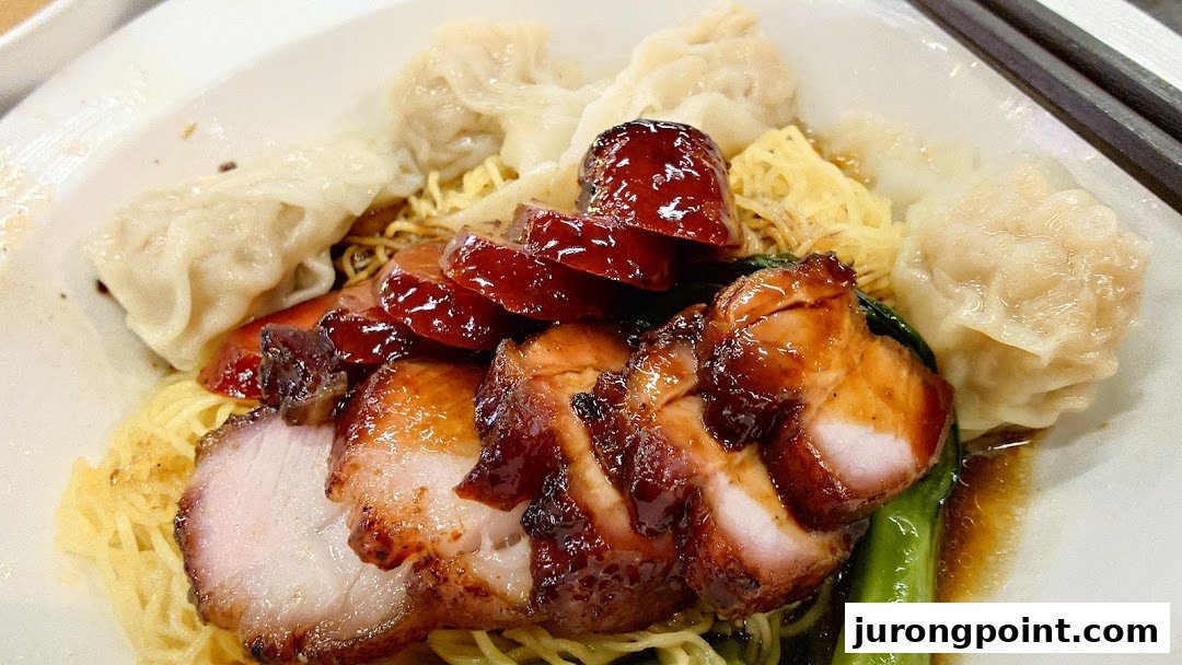 A close-up of a delicious plate of char siu wonton noodles with bok choy.
