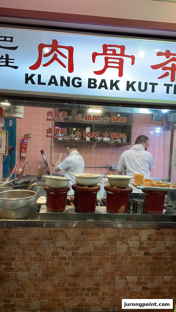 Chefs preparing food at a Klang Bak Kut Teh stall, with menu items and prices visible.