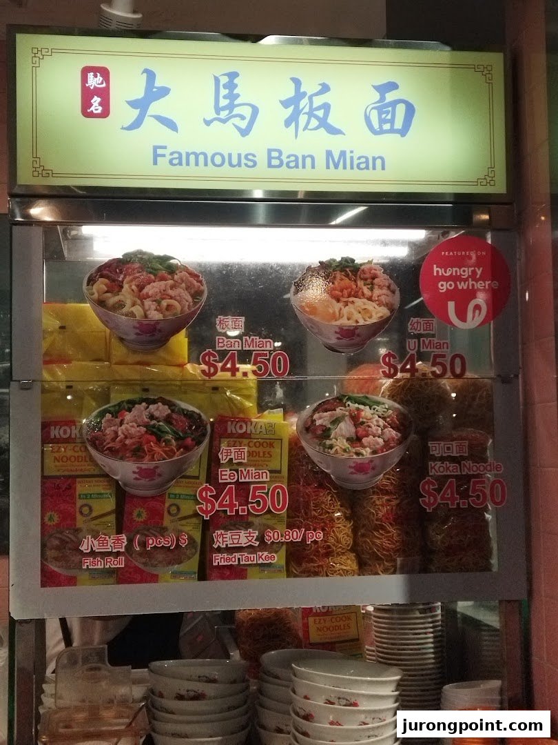 A display case showcasing various noodle dishes and side items with their prices.
