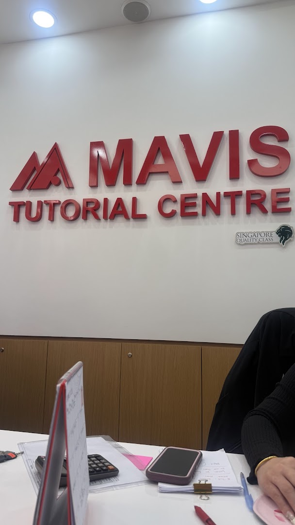 Interior view of Mavis Tutorial Centre featuring its prominent red logo on a white wall above a desk.