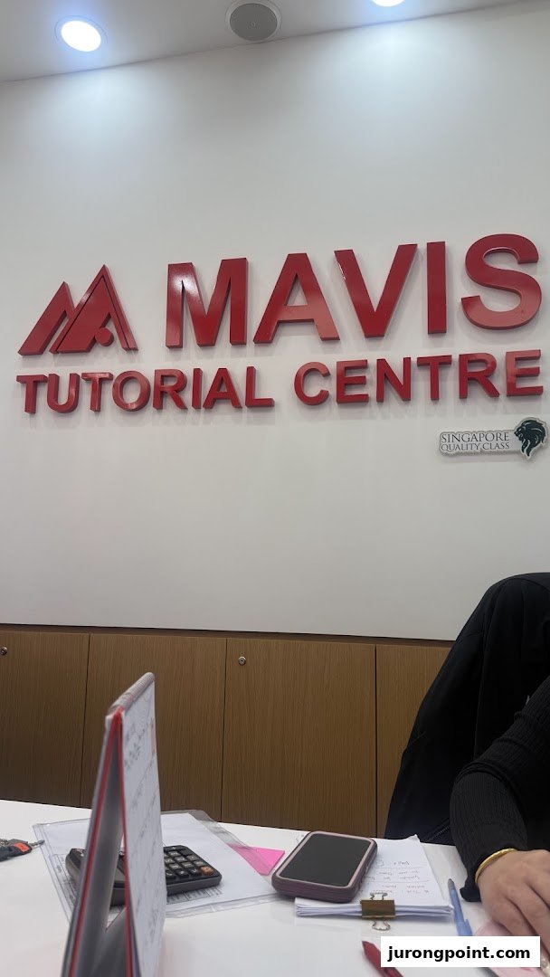 Interior view of Mavis Tutorial Centre featuring its prominent red logo on a white wall above a desk.