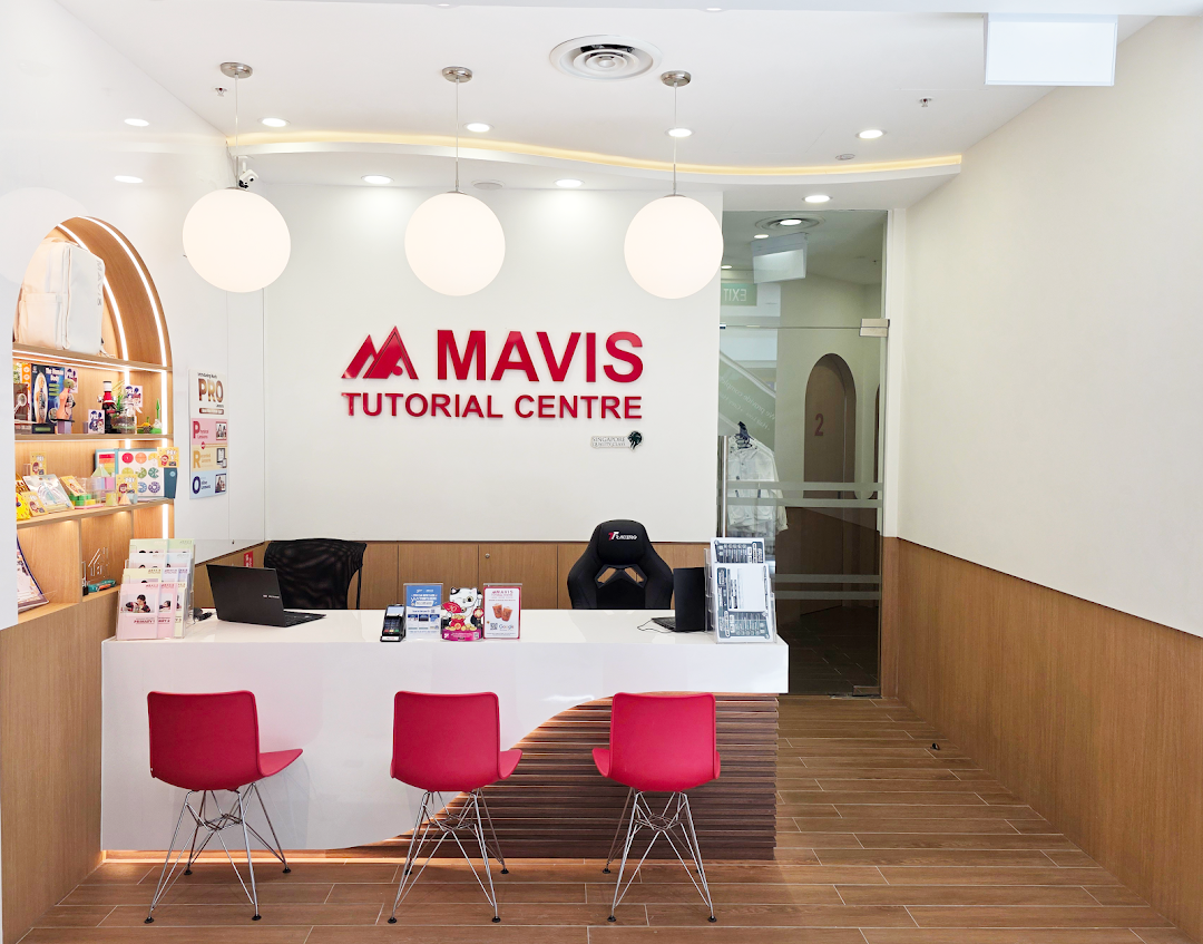 The bright, modern reception area of Mavis Tutorial Centre with a white desk and red chairs.