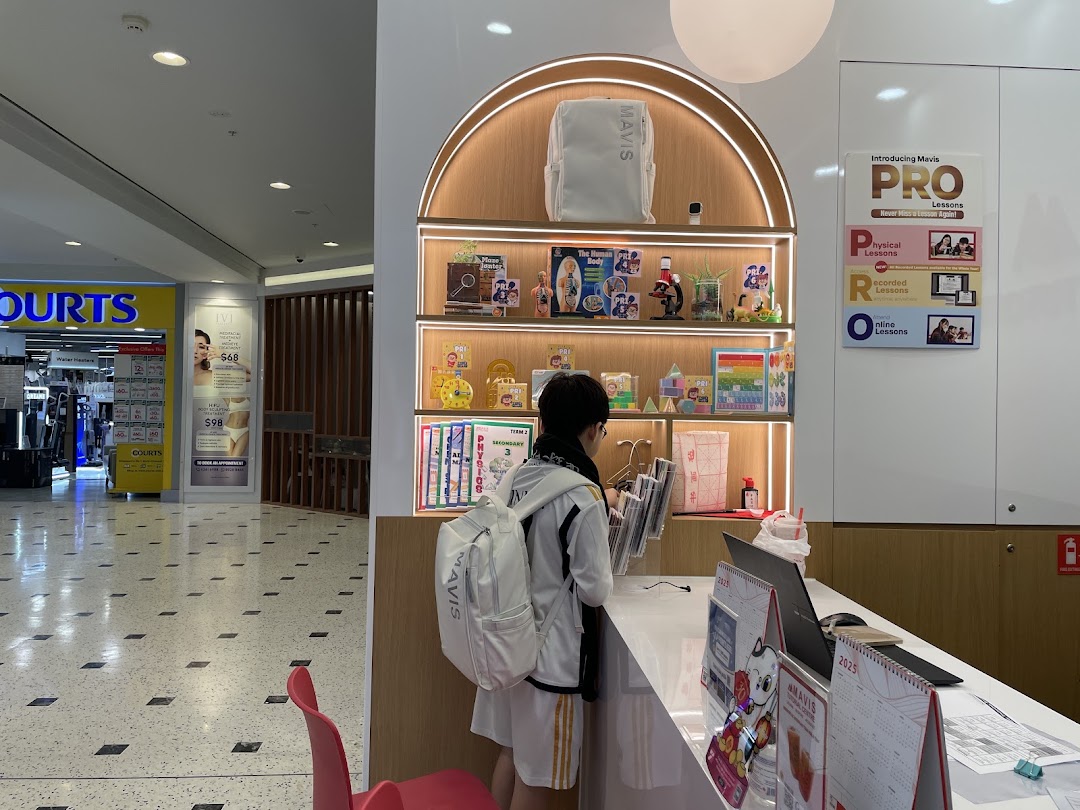 A student interacts with staff at the Mavis Tutorial counter, featuring educational displays and lesson information.