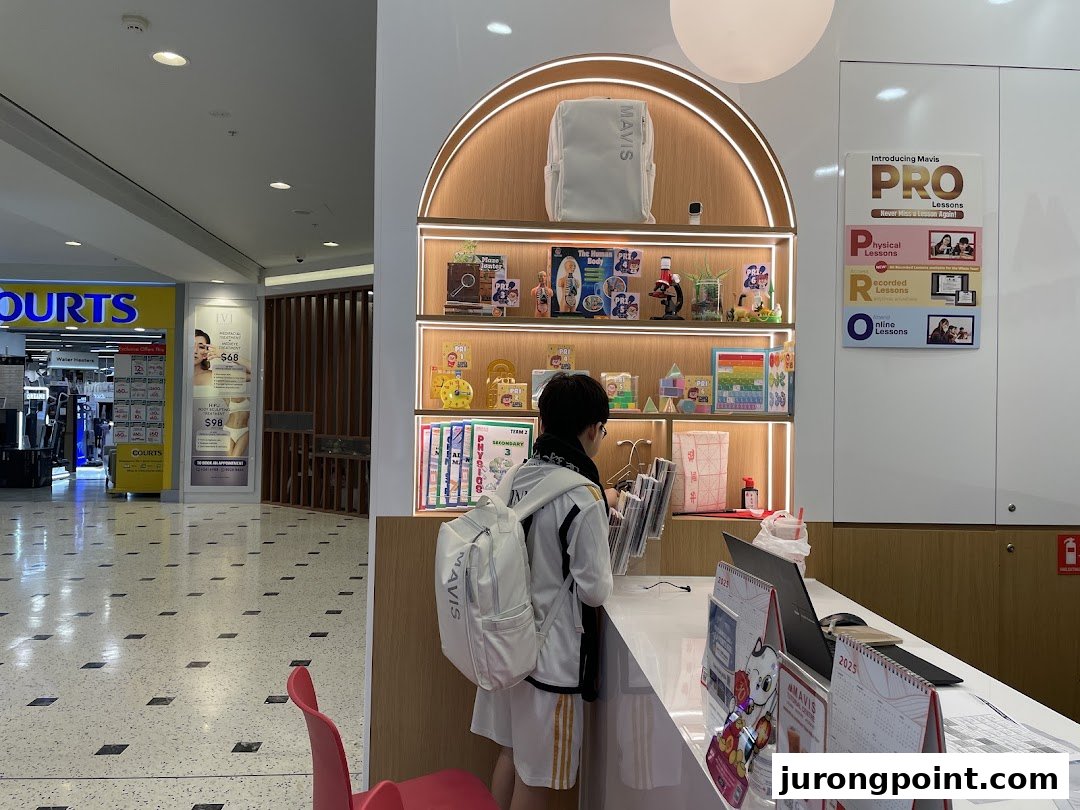 A student interacts with staff at the Mavis Tutorial counter, featuring educational displays and lesson information.