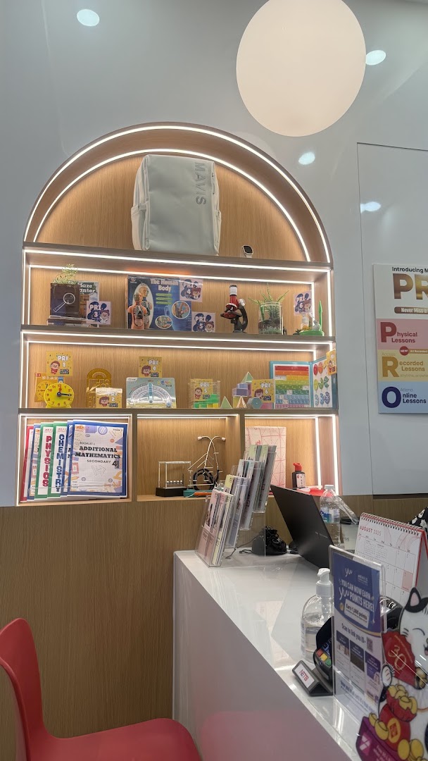 Interior view of Mavis Tutorial, showcasing educational materials on a brightly lit display shelf and a reception counter.