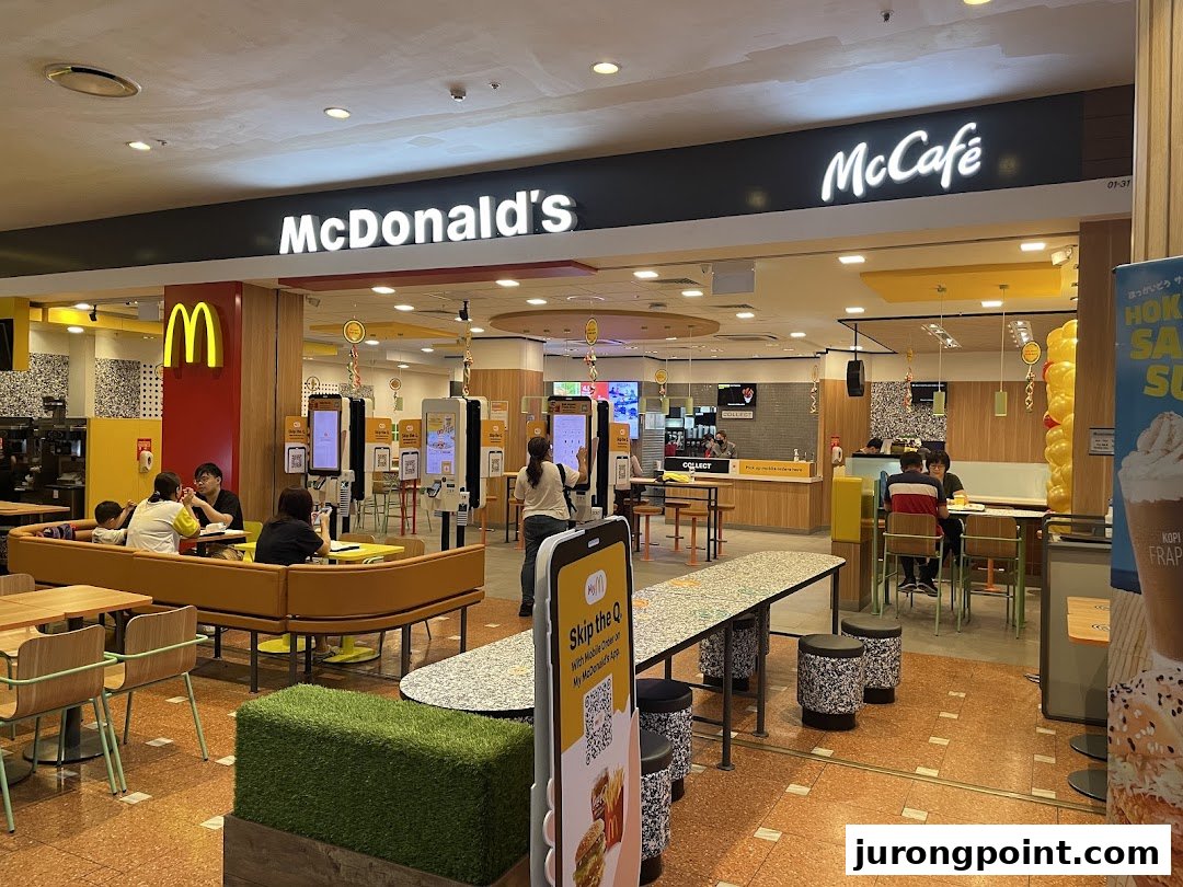 A bustling McDonald's interior featuring self-order kiosks, comfortable seating, and the McCafé section.