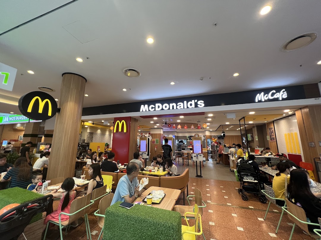 A bustling McDonald's interior with customers dining and the counter area visible.