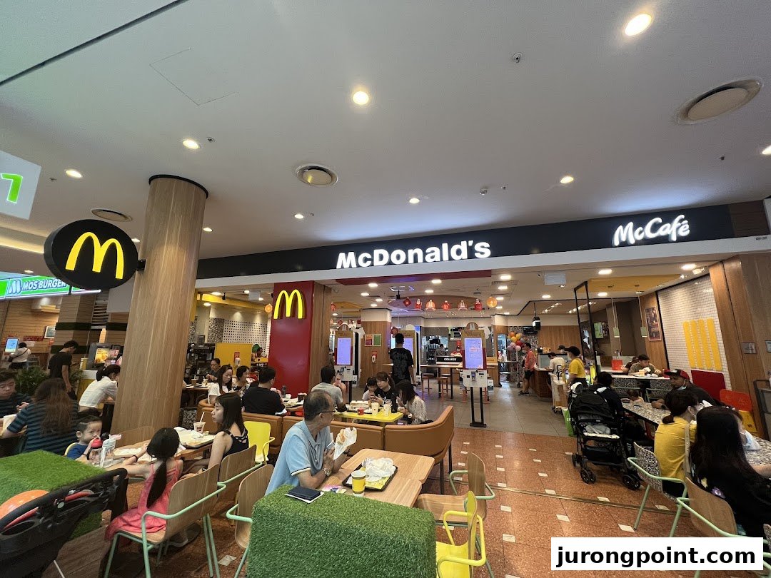 A bustling McDonald's interior with customers dining and the counter area visible.