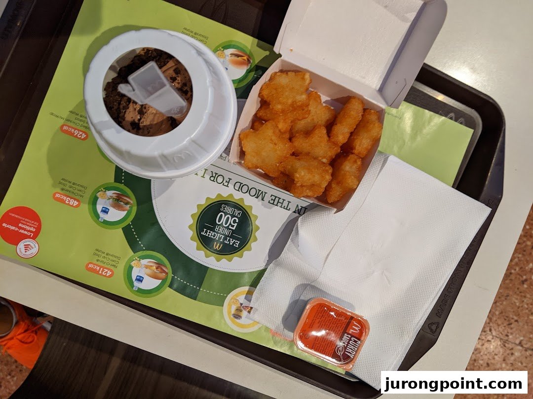A McDonald's meal featuring hash browns, a chocolate dessert, and curry sauce on a tray.