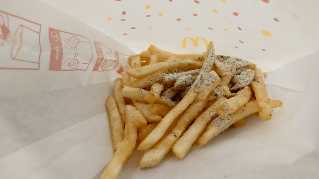 Close-up of seasoned McDonald's french fries inside a paper bag.