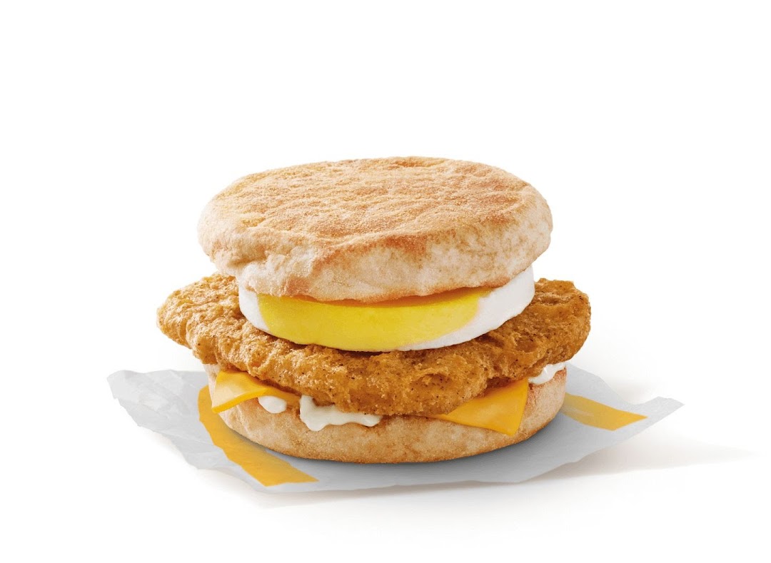 A close-up studio shot of a McDonald's breakfast sandwich with egg, chicken, and cheese.