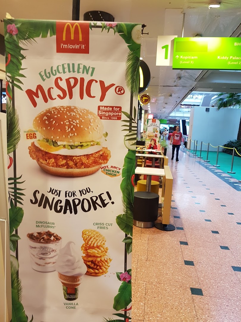 A McDonald's promotional banner in a mall featuring the Eggcellent McSpicy, McFlurry, fries, and vanilla cone.