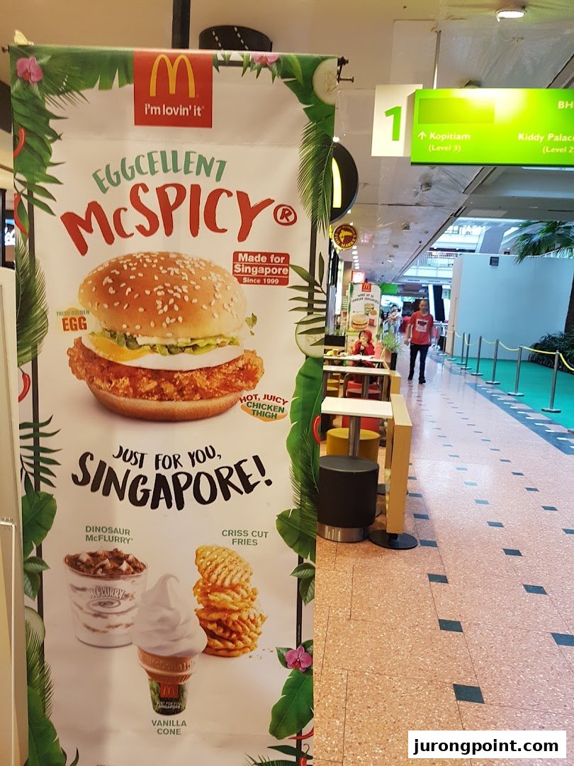 A McDonald's promotional banner in a mall featuring the Eggcellent McSpicy, McFlurry, fries, and vanilla cone.
