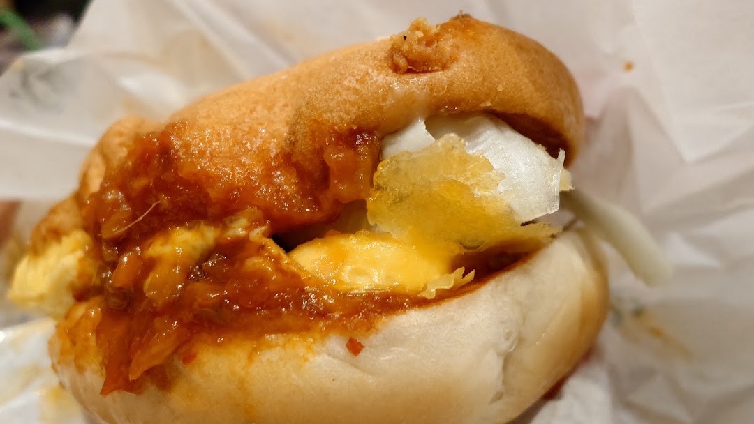 A close-up of a savory bun filled with rich sauce, melted cheese, and white ingredients.