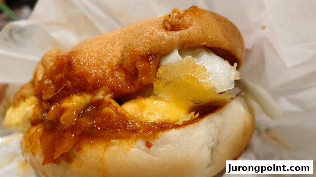 A close-up of a savory bun filled with rich sauce, melted cheese, and white ingredients.