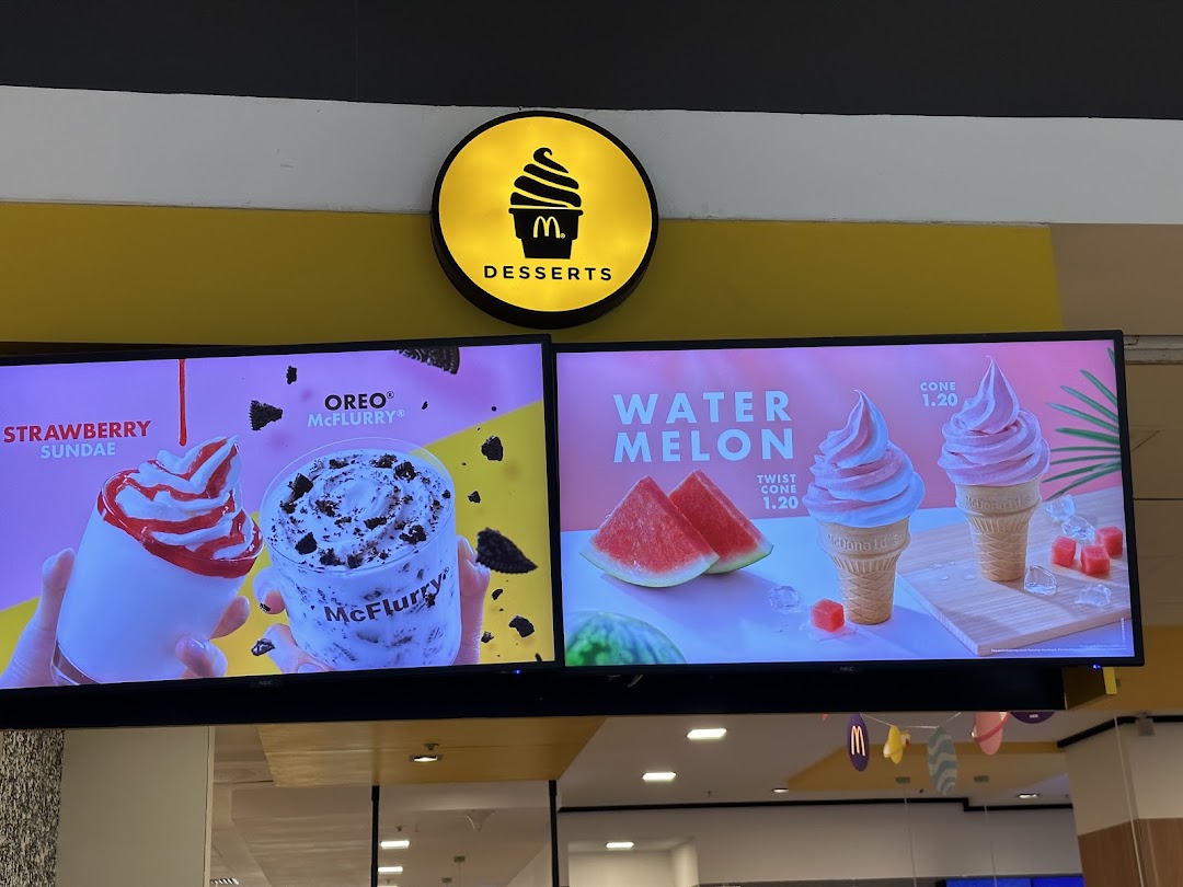 Digital menu boards at McDonald's showcasing a variety of delicious desserts including sundaes, McFlurries, and ice cream cones.