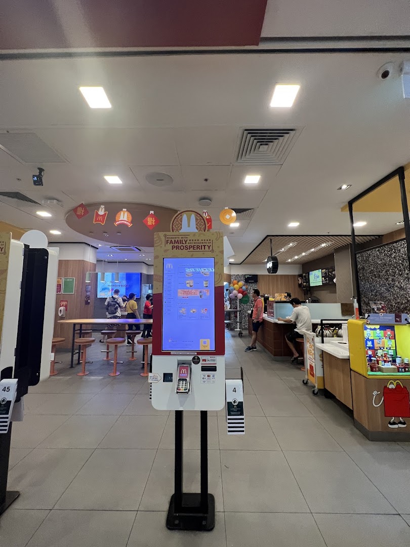 An interior view of a modern McDonald's restaurant featuring self-order kiosks and a service counter.