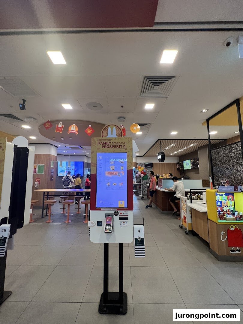 An interior view of a modern McDonald's restaurant featuring self-order kiosks and a service counter.