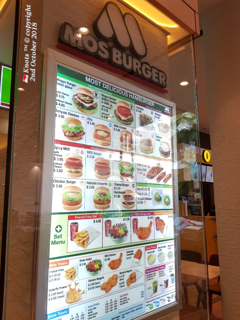 A brightly lit menu board displaying various burgers, sides, and drinks at MOS Burger.