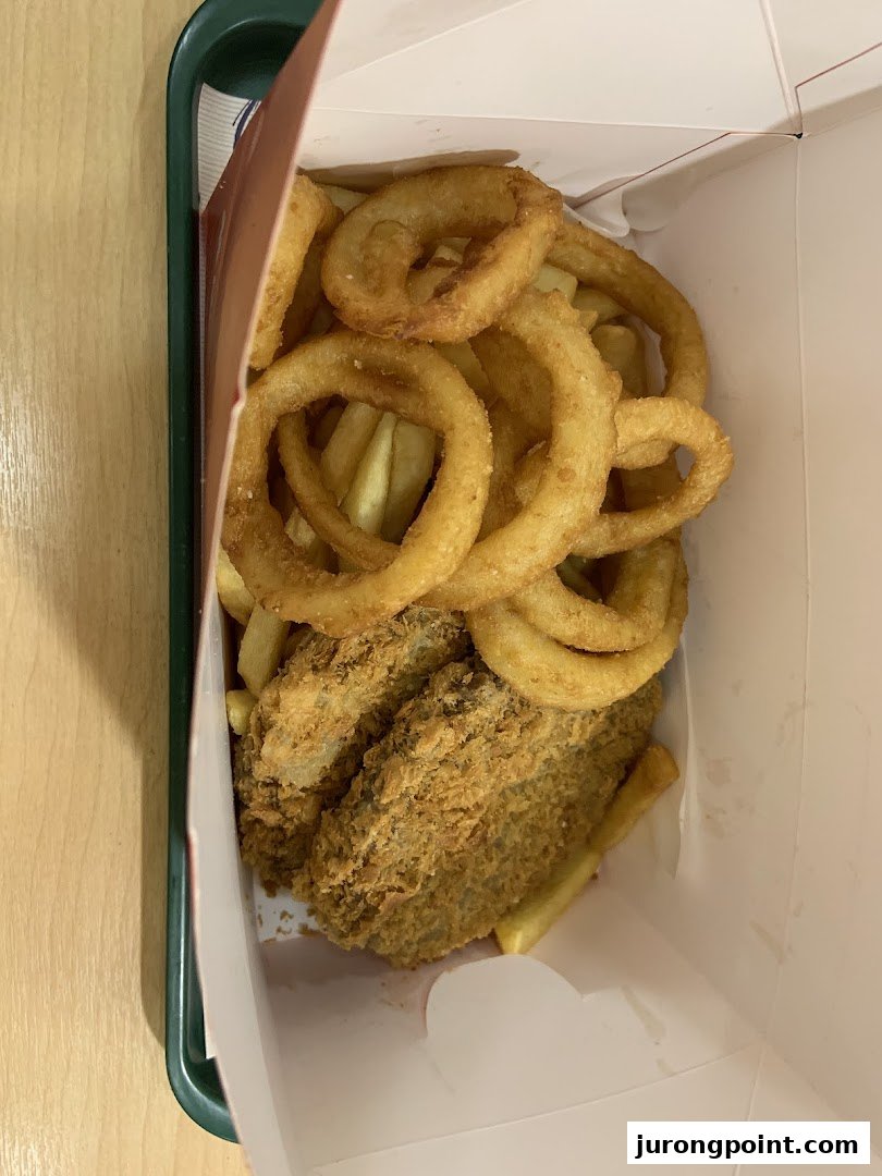 A box filled with golden fried onion rings, crispy fries, and breaded fish or chicken pieces.