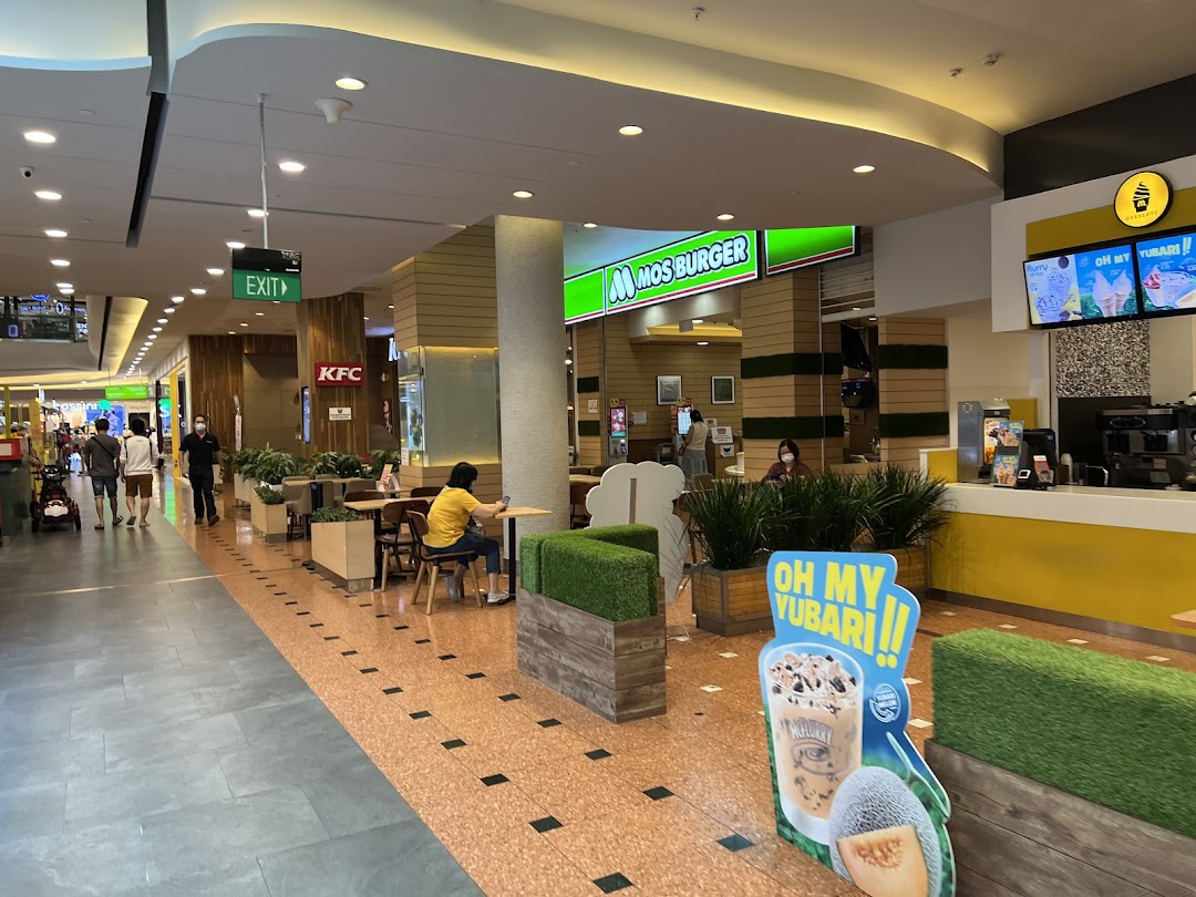 An interior view of MOS Burger in a mall, showing the counter, seating, and a promotional stand.
