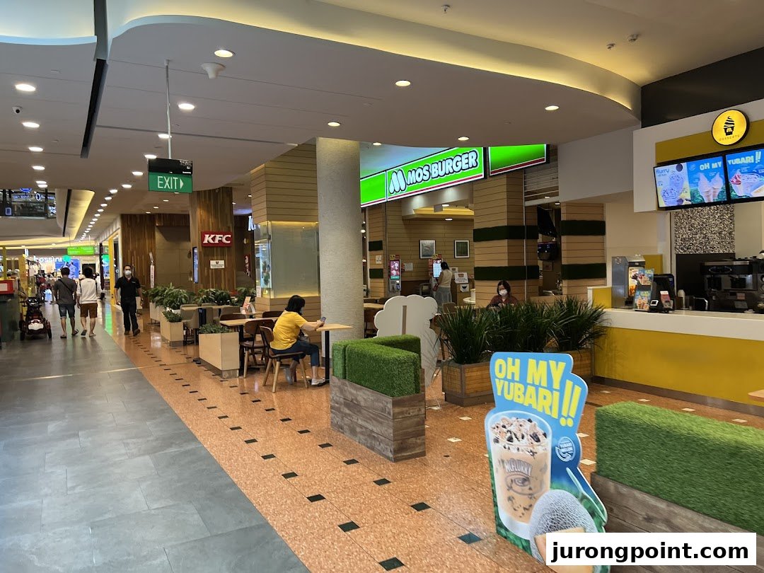 An interior view of MOS Burger in a mall, showing the counter, seating, and a promotional stand.