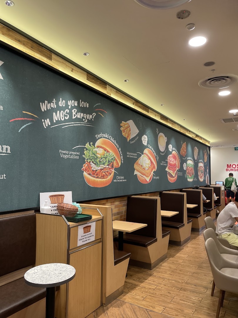 Interior view of MOS Burger featuring comfortable booth seating and a vibrant wall mural showcasing menu items.