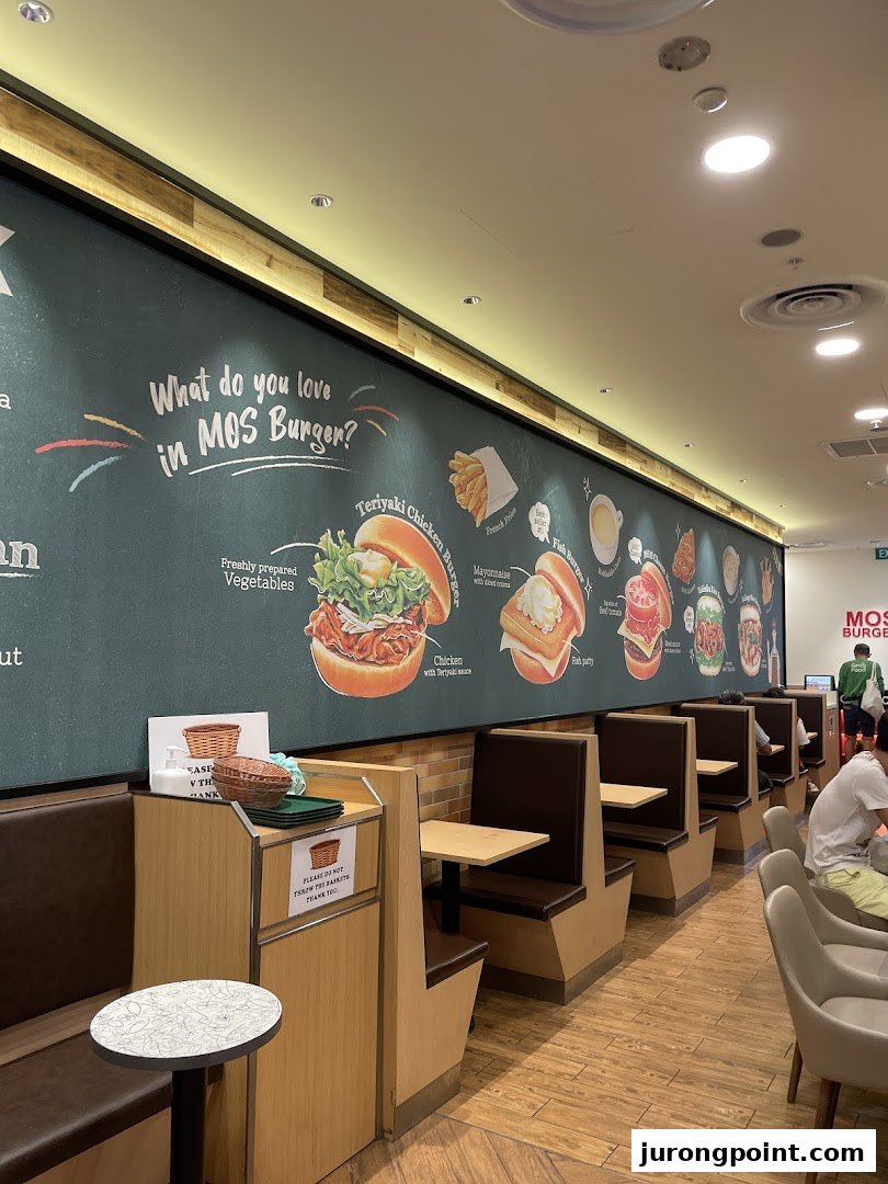 Interior view of MOS Burger featuring comfortable booth seating and a vibrant wall mural showcasing menu items.